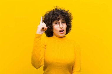 Genç ve güzel afro kadın bir fikri fark ettikten sonra mutlu ve heyecanlı bir dahi gibi hissediyor, neşeli bir şekilde parmağını kaldırıyor, eureka!