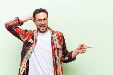 Genç yakışıklı adam gülüyor, mutlu, pozitif ve şaşırmış görünüyor. Yan fotokopi alanını işaret eden harika bir fikrin farkına varıyor.