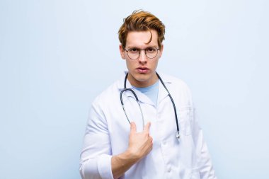 Genç kızıl kafalı doktor şaşkın, şaşkın ve güvensiz hissediyor. Kendini gösterip kim olduğumu soruyor. Ben mi? mavi duvara yaslan