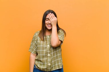 Genç ve güzel bir kadın gülüyor ve alnına şaplak atıyor. Unutmuşum yoksa turuncu duvara yapıştırılmış aptalca bir hataydı. 