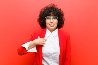 Genç, güzel afro kadın mutlu, gururlu ve şaşırmış görünüyor, neşeli bir şekilde kendini gösteriyor, kendinden emin ve yüce hissediyor.