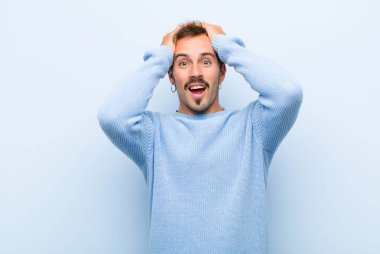 Genç yakışıklı adam el ele tutuşuyor, ağzı açık, kendini çok şanslı hissediyor, şaşırmış, heyecanlı ve mutlu.