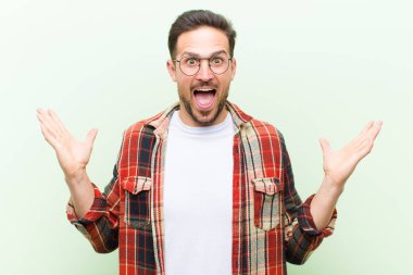 Genç yakışıklı adam mutlu ve heyecanlı görünüyor. Beklenmedik bir sürprizle şoke olmuş. İki eli yüzü açık.
