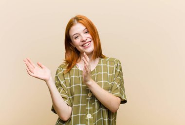 Genç kızıl saçlı güzel kadın mutlu ve başarılı hissediyor, gülümsüyor ve alkışlıyor, alkışlarla tebrik ediyor.