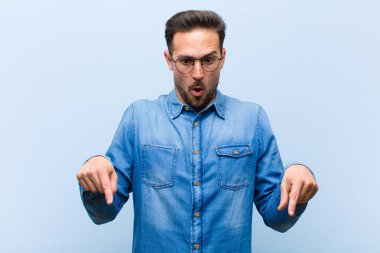 Genç yakışıklı adam şok olmuş, ağzı açık ve şaşkın, inançsızlık ve şaşkınlık içinde bakıyor ve onu işaret ediyor.