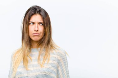 Genç, güzel bir kadın üzgün, üzgün ya da kızgın ve beyaz arka plana karşı anlaşmazlık içinde, olumsuz bir tavırla yan tarafa bakıyor.