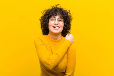 Genç, güzel afro kadın mutlu, pozitif ve başarılı hissediyor, bir meydan okumayla karşılaştığında motive oluyor veya iyi sonuçları kutluyor.