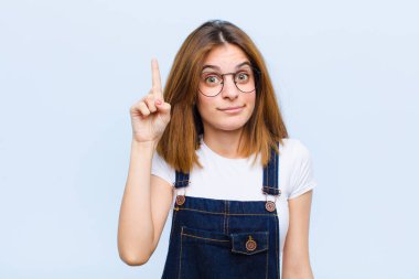 Genç ve güzel bir kadın, harika bir fikrin farkına vardıktan sonra mavi arka plana karşı 