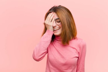 Genç ve güzel bir kadın gülüyor ve alnına şaplak atıyor. Unuttum yoksa pembe arka planda yaptığım aptalca bir hataydı. 