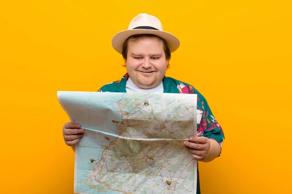 young big size man with a map against flat wall