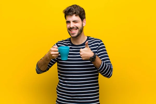 Joven hombre guapo tomando un café sobre fondo naranja — Foto de Stock