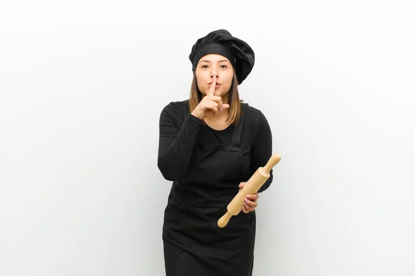 cook woman asking for silence and quiet, gesturing with finger in front of mouth, saying shh or keeping a secret against white background