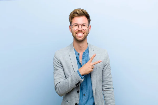 若いビジネスマンは幸せでポジティブで成功しV字型を胸に手で作り勝利や青い背景に平和を示す — ストック写真