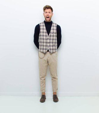 Genç vücut adamı korkmuş ve şok olmuş hissediyor, ağzı açık beyaz arka plana karşı şaşkınlık içinde.