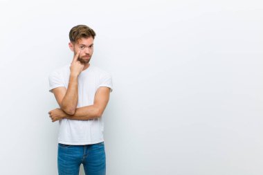 Genç adam sana göz kulak oluyor, güvenmiyor, izliyor, tetikte ve beyaz arka plana karşı tetikte.