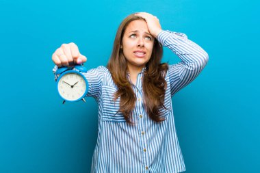 mavi arka plan karşı çalar saat ile genç kadın