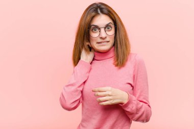 Genç, güzel bir kadın kendini stresli, hayal kırıklığına uğramış ve yorgun hissediyor. Pembe arka planda endişeli ve sorunlu bir bakışla boynunu okşuyor.