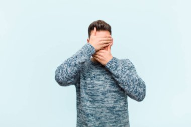 Genç İspanyol adam kameraya hayır diyen iki eliyle yüzünü kapatıyor! Resimler reddediliyor ya da mavi arkaplana karşı resimler yasaklanıyor