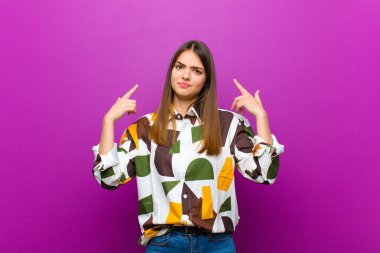 Kötü tavrı olan genç ve güzel bir kadın gururlu ve agresif görünüyor, yukarı bakıyor ya da elleri mor arka planda alay işareti yapıyor.