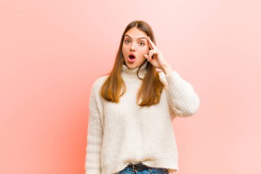 Genç, güzel bir kadın şaşırmış, ağzı açık, şok olmuş, pembe arka plana karşı yeni bir düşünce, fikir ya da konsept keşfediyor.