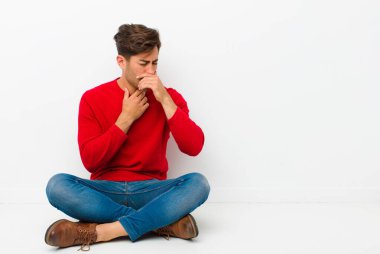 Genç ve yakışıklı bir adam boğazı ağrıyormuş ve grip belirtileri gösteriyormuş. Ağzı yere kapalıyken öksürüyormuş.