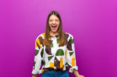 Genç, güzel bir kadın agresif bir şekilde bağırıyor, sinirli, sinirli, öfkeli ya da sinirli görünüyor, mor arka plana hayır diye bağırıyor.