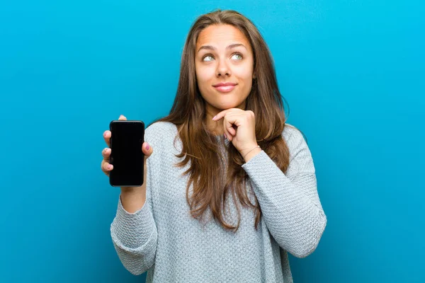 Giovane donna con un telefono cellulare sullo sfondo blu — Foto Stock