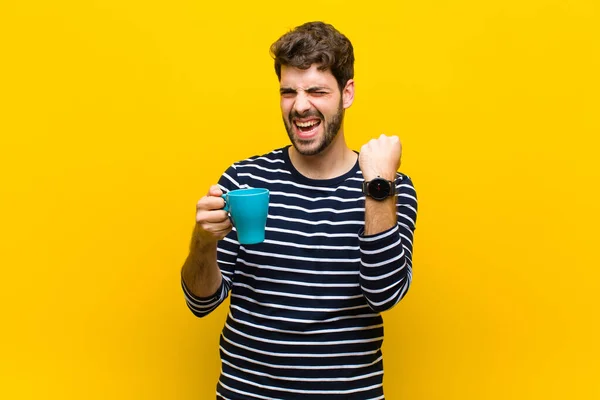 Mladý pohledný muž s kávou na oranžovém pozadí — Stock fotografie