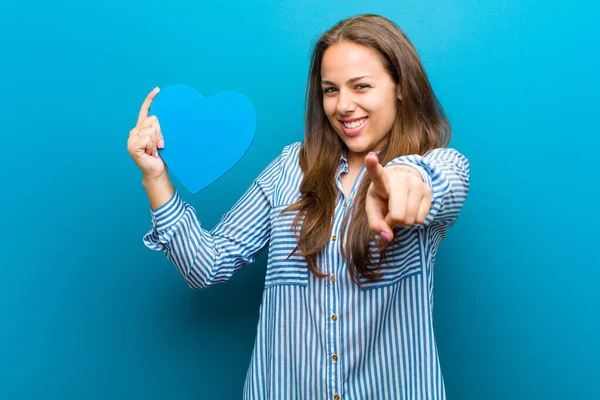 Junge Frau mit Herzform vor blauem Hintergrund — Stockfoto
