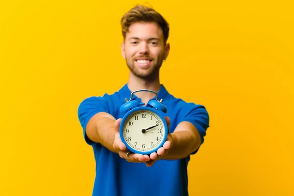 Junger Mann Mit Wecker Vor Orangefarbenem Hintergrund — Stockfoto