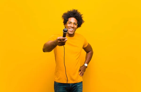Ung afrikansk amerikansk man med en mikrofon som sjunger emot eller — Stockfoto