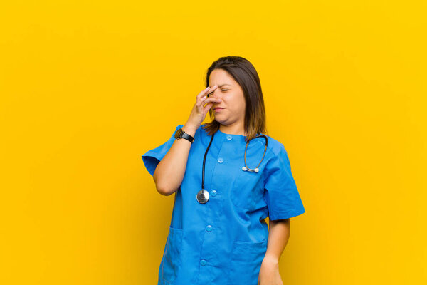 feeling disgusted, holding nose to avoid smelling a foul and unpleasant stench isolated against yellow wall