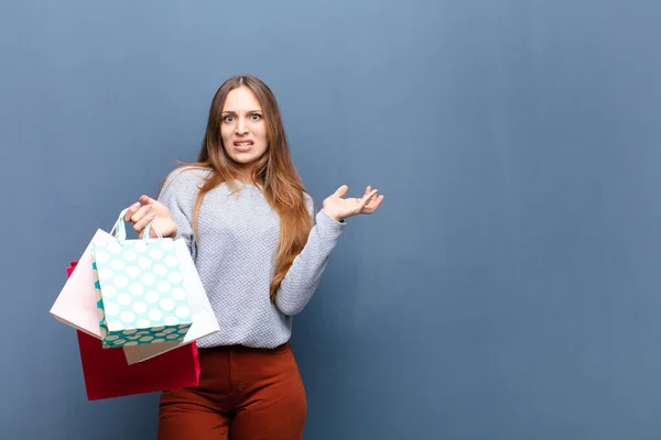 コピースペースのある青い壁に買い物袋を持った若い可愛い女性 — ストック写真