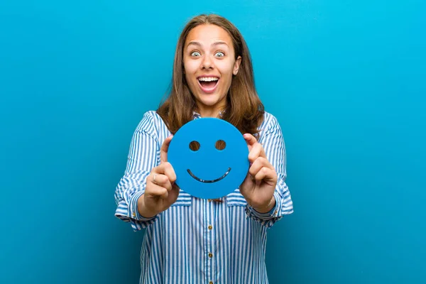 Jonge vrouw met een smiley gezicht tegen blauwe achtergrond — Stockfoto