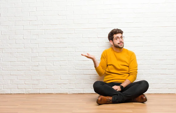 Joven Hombre Guapo Sentado Suelo Casa Contra Textura Pared Ladrillo —  Fotos de Stock