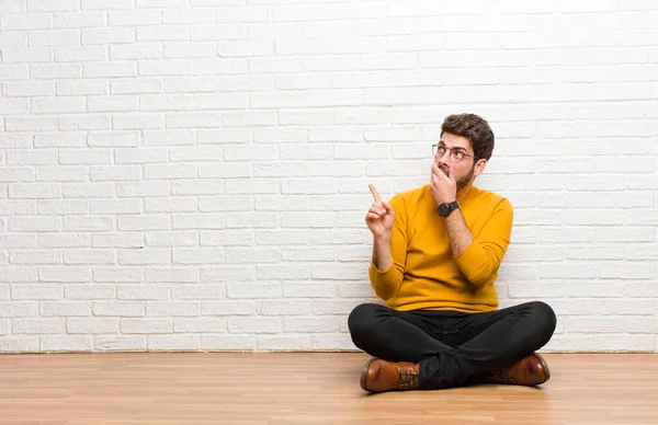 Joven Hombre Guapo Sentado Suelo Casa Contra Textura Pared Ladrillo —  Fotos de Stock