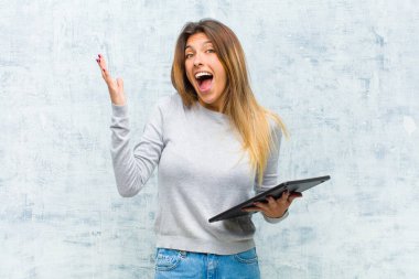# Genç ve güzel bir kadın, tabletle grunge duvarına yaslanmış #