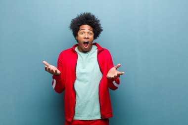 Genç siyah sporcu son derece şok olmuş ve şaşırmış, endişeli ve paniklemiş hissediyor. Stresli ve dehşetli bir bakışla grunge duvarına bakıyor.