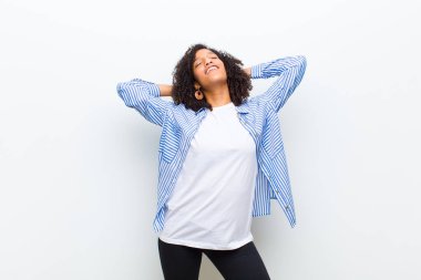 Genç, afro-amerikan kadın gülümsüyor ve rahatlıyor, tatmin oluyor ve kaygısızca gülüyor.