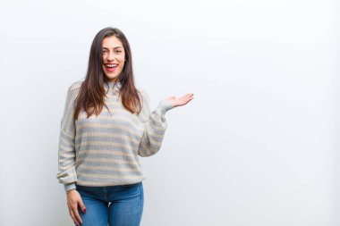 Genç, güzel bir kadın kendini mutlu, şaşırmış ve neşeli hissediyor. Pozitif bir tavırla gülümsüyor. Beyaz duvarda izole edilmiş bir çözüm ya da fikri fark ediyor.