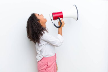 Beyaz duvarda megafonu olan genç, güzel siyah bir kadın.