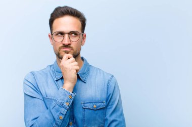 Genç yakışıklı adam düşünceli, meraklı ya da hayal kuruyor, hayal kuruyor ve mekanı kopyalamak için yukarı bakıyor.