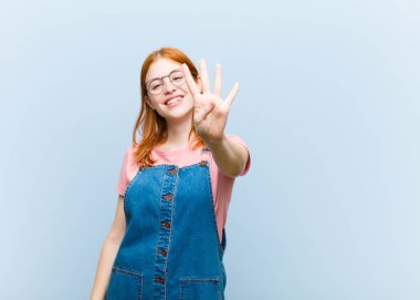 Genç kızıl saçlı güzel bir kadın gülümsüyor ve arkadaş canlısı görünüyor, dört ya da dört numarayı gösteriyor, eli önde, geri sayıyor.