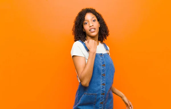 若いかなり黒人女性はストレスを感じ 不安を感じ 不満を感じ シャツの首を引っ張り オレンジの壁に対する問題に不満を感じ — ストック写真