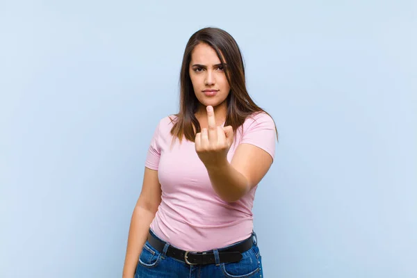 若い女性は怒り いらいらし 反抗的で攻撃的で 真ん中の指をひっくり返し 青い背景と戦っています — ストック写真