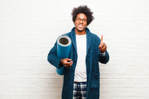 Молодой черный мужчина в пижаме с ковриком для йоги — стоковое фото