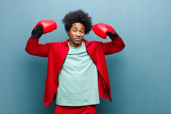 Giovane uomo nero con guanti da boxe contro muro grunge blu — Foto Stock