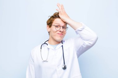 Genç kızıl kafa doktor, aptalca bir hata yaptıktan ya da hatırladıktan sonra mavi duvara karşı kendini aptal hissederek avuç avuç içini kaldırıyor.