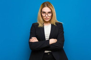 Genç, güzel, sarışın bir kadın bilgisiz ve kafası karışık, bir çözüm düşünüyor, eli kalçasında, diğeri kafasında, düz duvara karşı dikiz aynasıyla.