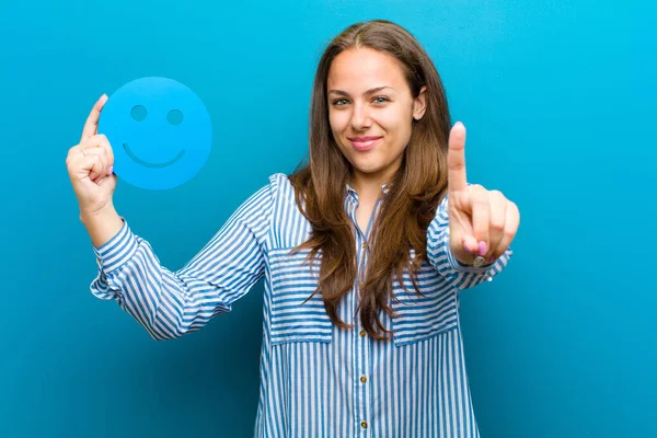 Giovane donna con un volto sorridente sullo sfondo blu — Foto Stock